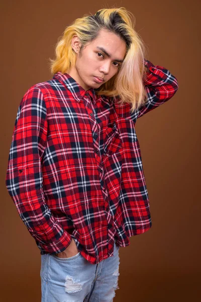 Jovem asiático vestindo roupas elegantes contra fundo marrom — Fotografia de Stock