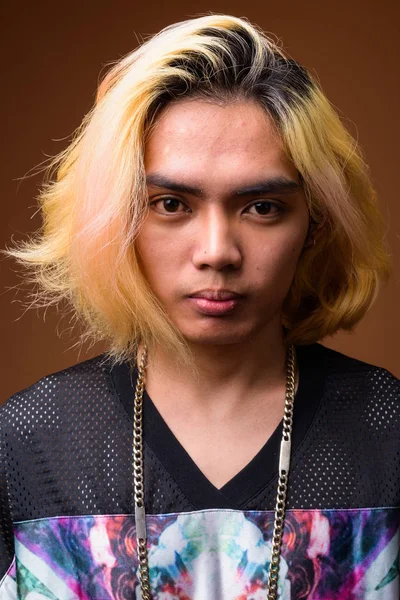 Jovem asiático vestindo roupas elegantes contra fundo marrom — Fotografia de Stock