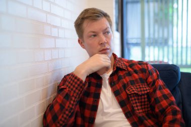 Kahve dükkanında pencereden görünen genç düşünceli Hipster adam