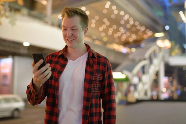 Ο άνθρωπος νεαρός ευτυχισμένη Hipster χρησιμοποιώντας τηλέφωνο στην πόλη τη νύχτα — Φωτογραφία Αρχείου