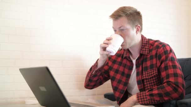 Fiatal csípő ember kávét iszik, és a telefon használata a kávézóban — Stock videók