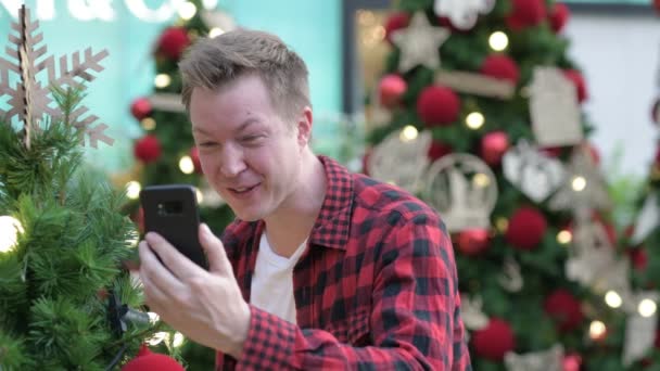 Happy Young Man videollamadas y tomando fotos de árboles de Navidad al aire libre — Vídeo de stock