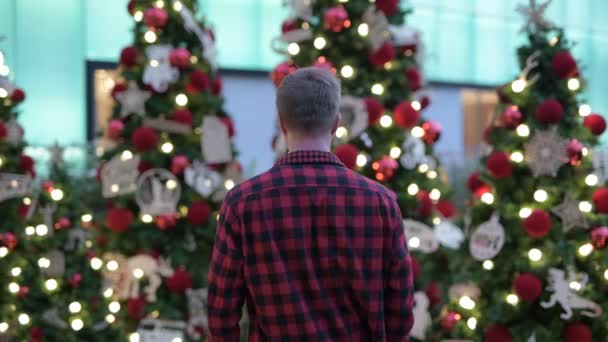 Joven hombre feliz Hipster con los brazos levantados contra los árboles de Navidad al aire libre — Vídeo de stock