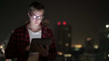 Düşünme ve geceleri şehir manzarasına karşı dijital Tablet kullanarak mutlu Hipster adam