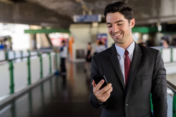 Portrait of happy businessman in city using mobile phone — Stock Photo, Image