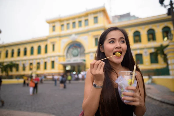 Asian woman eating in front of Saigon Central Post Office — Stock Photo, Image