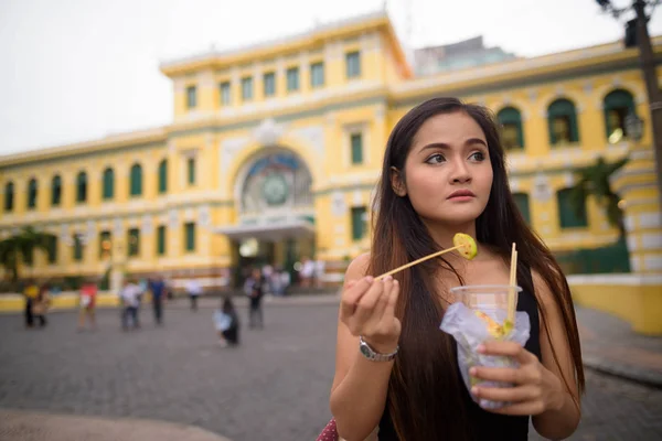 Asiatisk kvinna äta framför Saigon Central Post Office — Stockfoto