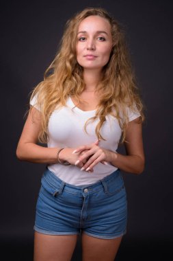 Gri bac karşı uzun dalgalı sarı saçlı Genç güzel kadın