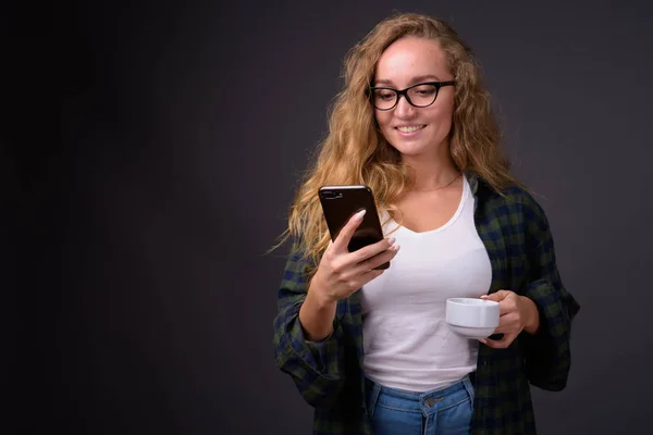 Young beautiful woman with long wavy blond hair using mobile phone — Stock Photo, Image