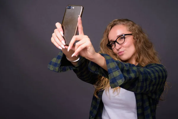 Cep telefonu kullaranarak uzun dalgalı sarı saçlı Genç güzel kadın — Stok fotoğraf