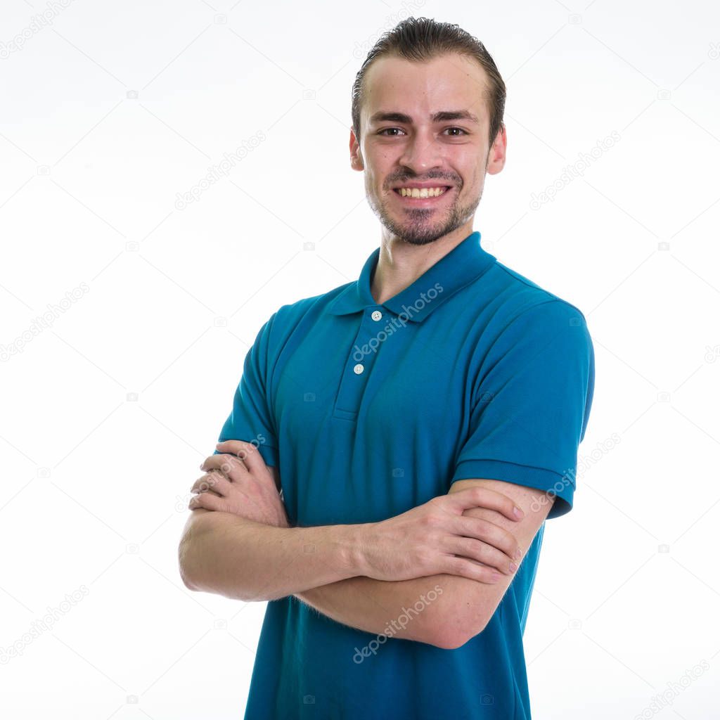Studio shot of young happy bearded man smiling with arms crossed against white background