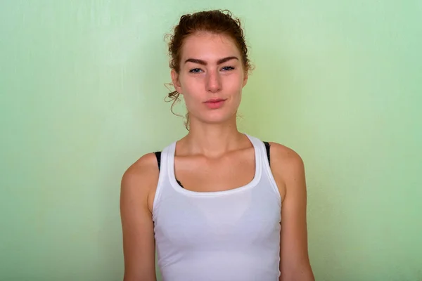 Studio shot of beautiful teenage girl with hair tied against gre