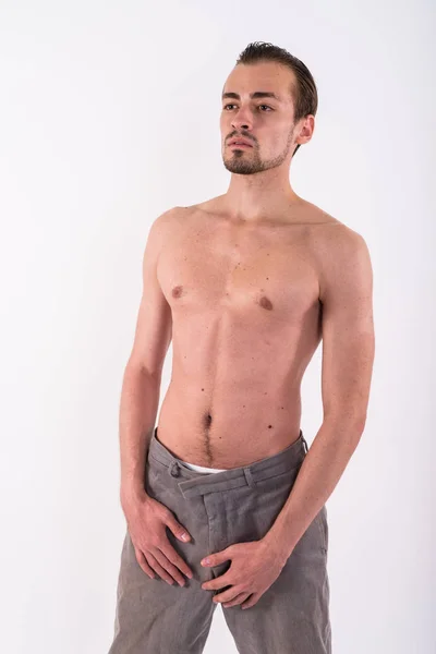 Studio shot of young bearded man standing and thinking while loo — Stock Photo, Image