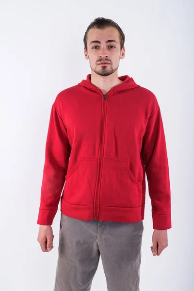 Studio shot of young bearded man wearing red hoodie against whit — Stock Photo, Image