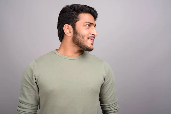 Porträt eines jungen gutaussehenden indischen Mannes, der vor grauem Hintergrund denkt — Stockfoto