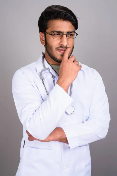 Porträt eines indischen Arztes, der vor grauem Hintergrund denkt — Stockfoto