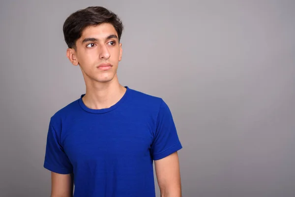 Junger gutaussehender persischer Teenager denkt vor grauem Hintergrund — Stockfoto