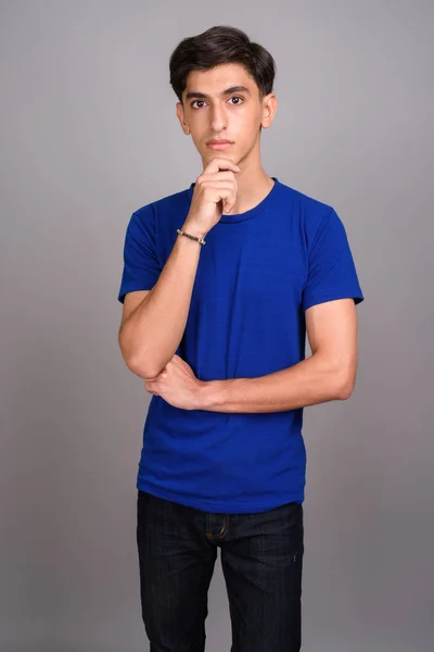 Young handsome Persian teenage boy against gray background — Stock Photo, Image