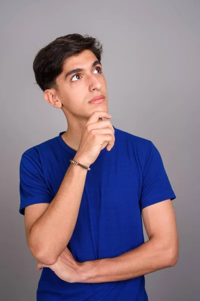 Young handsome Persian teenage boy thinking against gray background — Stock Photo, Image