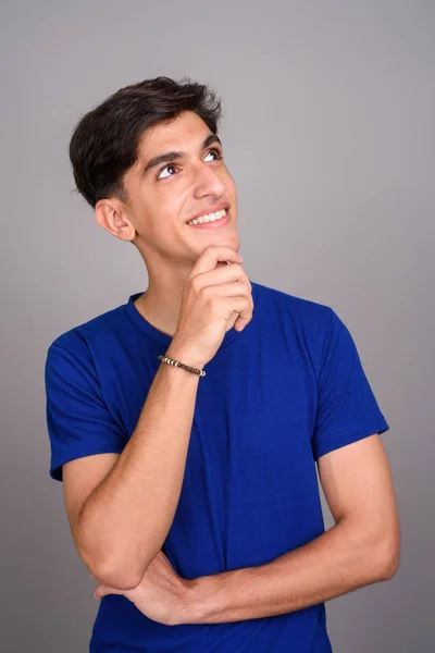 Young happy Persian teenage boy smiling against gray background — Stock Photo, Image