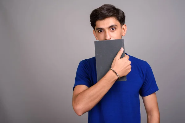 Jovem bonito persa adolescente estudante segurando livro — Fotografia de Stock