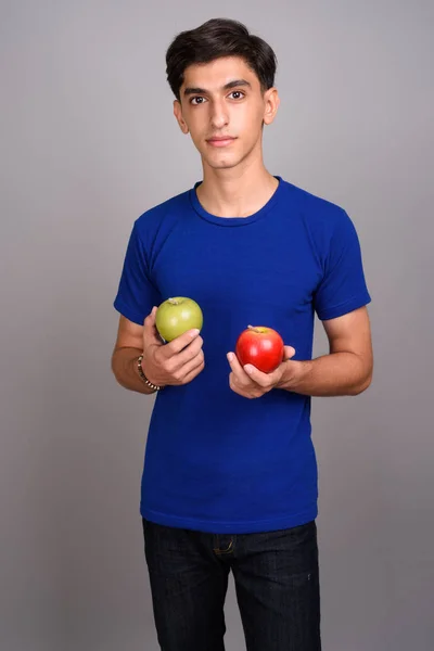 Joven guapo adolescente persa sosteniendo saludable manzana verde y roja —  Fotos de Stock