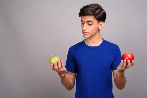 Jovem bonito adolescente persa segurando saudável maçã verde e vermelha — Fotografia de Stock
