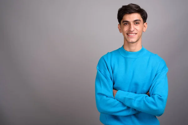 Jovem feliz adolescente persa sorrindo contra fundo cinza — Fotografia de Stock