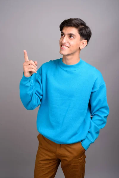 Jovem feliz adolescente persa sorrindo e apontando o dedo para cima — Fotografia de Stock