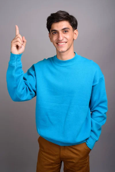 Fiatal boldog perzsa tizenéves fiú mosolyogva, és felfelé mutató ujj — Stock Fotó