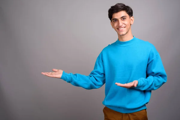 Young happy Persian teenage boy smiling and showing copyspace — Stock Photo, Image