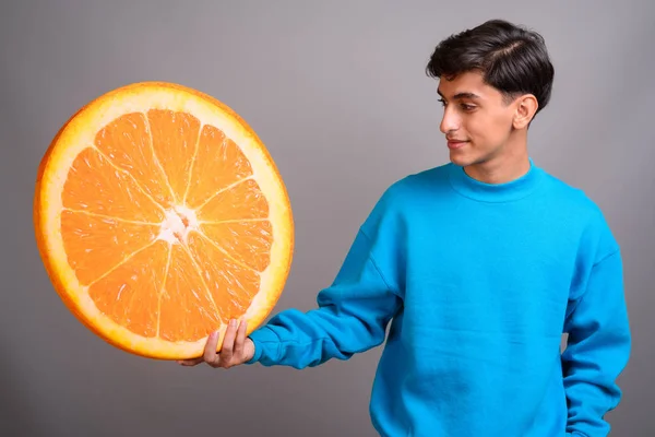 Joven adolescente persa sosteniendo gran rebanada de fruta naranja — Foto de Stock