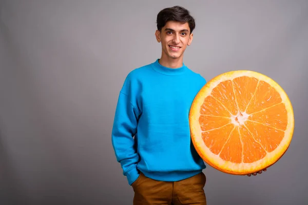 Jovem adolescente persa segurando grande fatia de fruta laranja — Fotografia de Stock