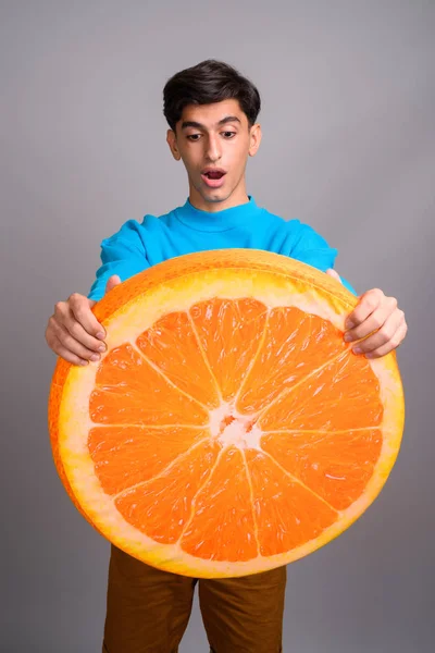 Jovem adolescente persa segurando grande fatia de fruta laranja — Fotografia de Stock
