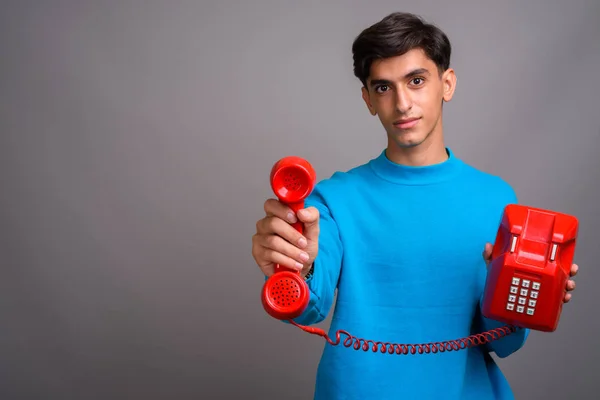 Giovane bel ragazzo adolescente persiano che parla sul vecchio telefono rosso — Foto Stock