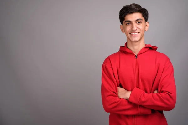 Young happy Persian teenage boy smiling with arms crossed — Stock Photo, Image