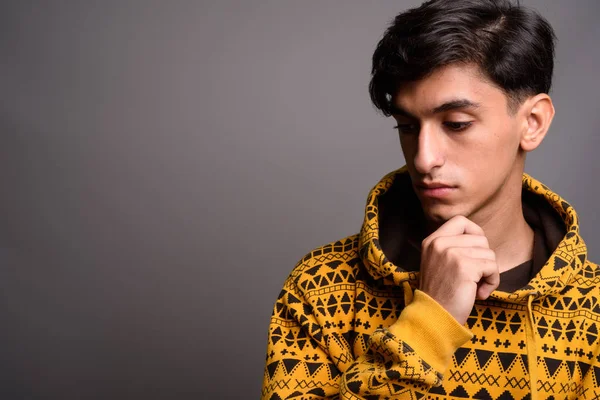 Triste ragazzo adolescente persiano che pensa contro sfondo grigio — Foto Stock