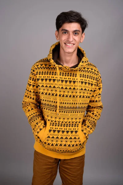 Jovem feliz adolescente persa sorrindo contra fundo cinza — Fotografia de Stock