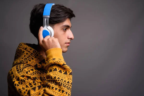 Profile view of young handsome Persian teenage boy with headphones — Stock Photo, Image