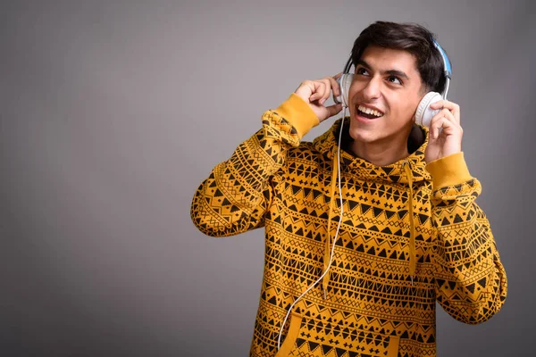 Junge glückliche persische Teenager lächeln und hören Musik mit Kopfhörern — Stockfoto