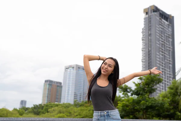 Jonge mooie Aziatische vrouw ontspannen in het park met opgeheven armen — Stockfoto