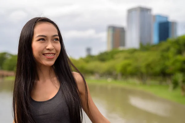 Jeune belle femme asiatique souriant et pensant au parc — Photo