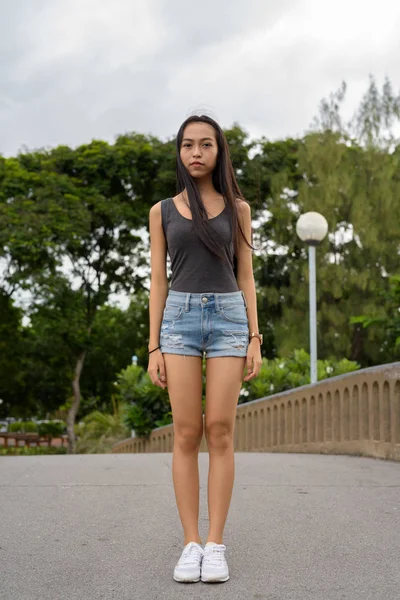 Volledige lengte schot van jonge mooie Aziatische vrouw ontspannen in het park — Stockfoto