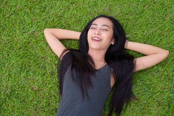 Feliz joven hermosa mujer asiática acostada en la hierba en el parque —  Fotos de Stock