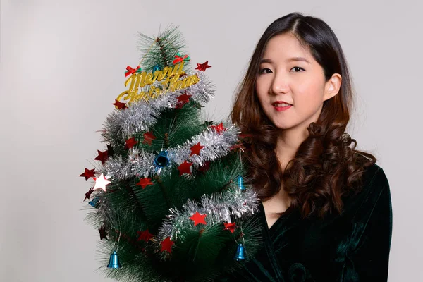 若いです幸せなアジアの女性を保持メリークリスマスツリー — ストック写真