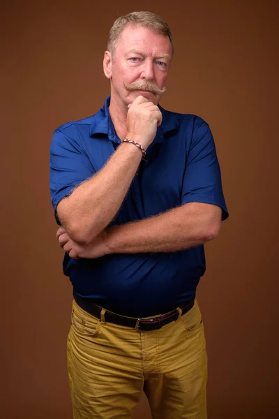 Bonito homem sênior com bigode contra fundo marrom — Fotografia de Stock