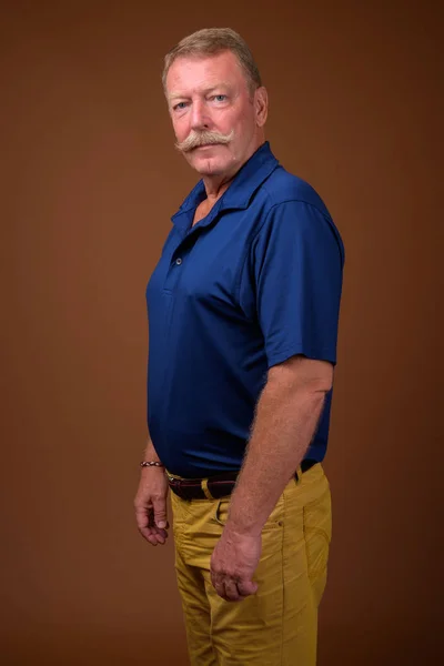 Przystojny starszy mężczyzna z wąsem brązowym tle — Zdjęcie stockowe