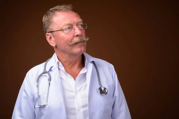 Bello anziano medico uomo con i baffi pensando e guardando in alto — Foto Stock