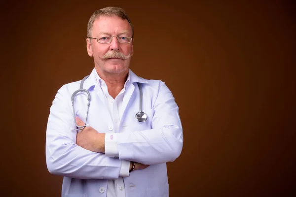 Bello anziano uomo medico con le braccia incrociate — Foto Stock