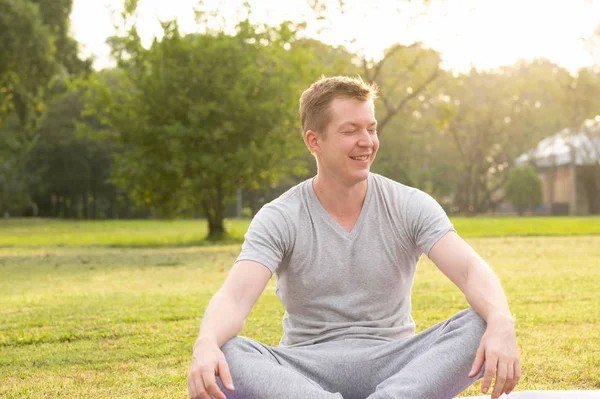 Joven hombre feliz relajándose con los ojos cerrados en el parque —  Fotos de Stock